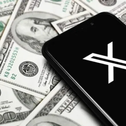 Smartphone displaying the X logo on U.S. dollar bills, illustrating X Money digital banking services nationwide.