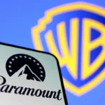 Paramount logo on smartphone with Warner Bros. shield blurred in background, symbolizing merger deal