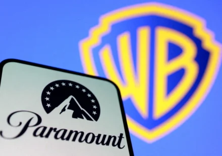 Paramount logo on smartphone with Warner Bros. shield blurred in background, symbolizing merger deal