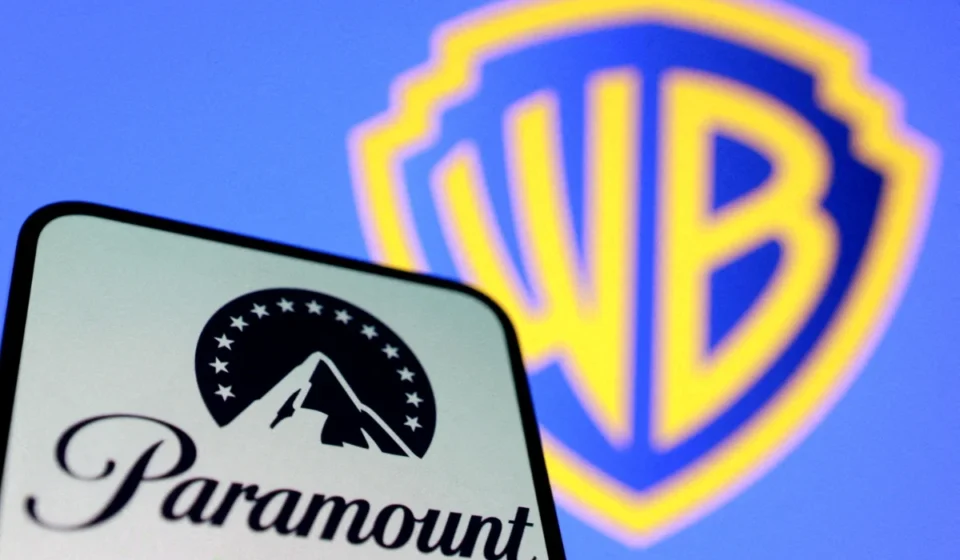 Paramount logo on smartphone with Warner Bros. shield blurred in background, symbolizing merger deal