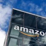 Amazon logo displayed on a modern glass office building as company expands satellite connectivity AI