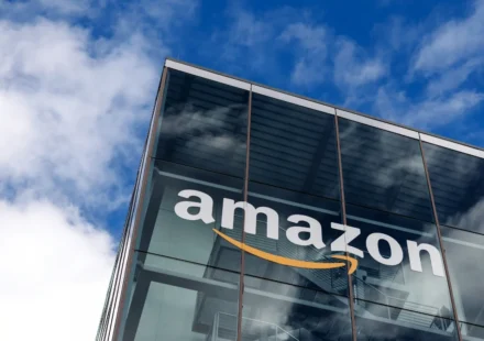 Amazon logo displayed on a modern glass office building as company expands satellite connectivity AI