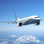 Boeing 737 passenger jet flying above clouds beneath a clear blue sky during a demonstration flight.