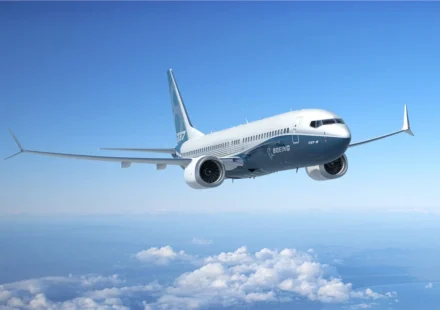 Boeing 737 passenger jet flying above clouds beneath a clear blue sky during a demonstration flight.