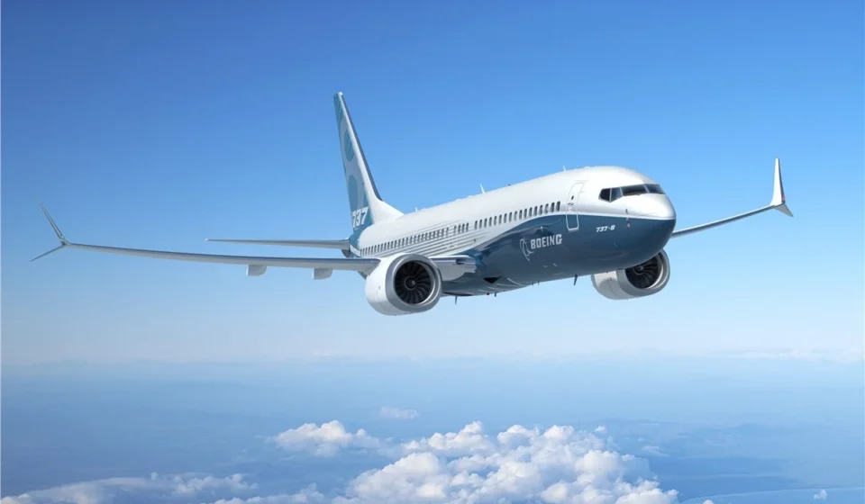 Boeing 737 passenger jet flying above clouds beneath a clear blue sky during a demonstration flight.