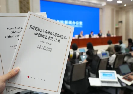 Hand holding China's global governance white paper during an international press briefing in Beijing.