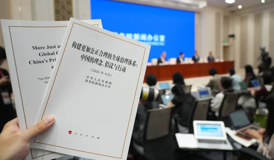 Hand holding China's global governance white paper during an international press briefing in Beijing.
