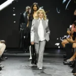 Fashion model leads runway show as audience records the launch of new sustainable fashion collection.