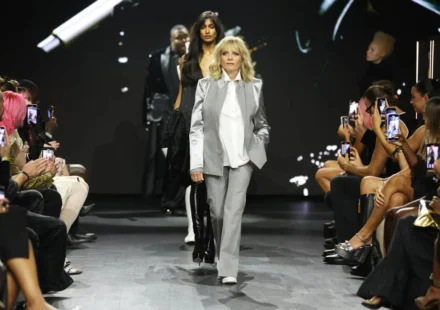 Fashion model leads runway show as audience records the launch of new sustainable fashion collection.