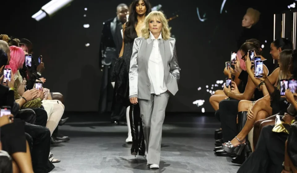 Fashion model leads runway show as audience records the launch of new sustainable fashion collection.