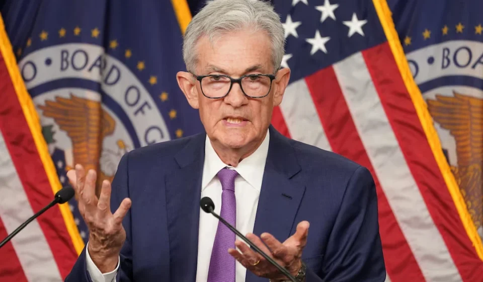 Federal Reserve Chair speaks after holding interest rates steady with US flags displayed behind podium.