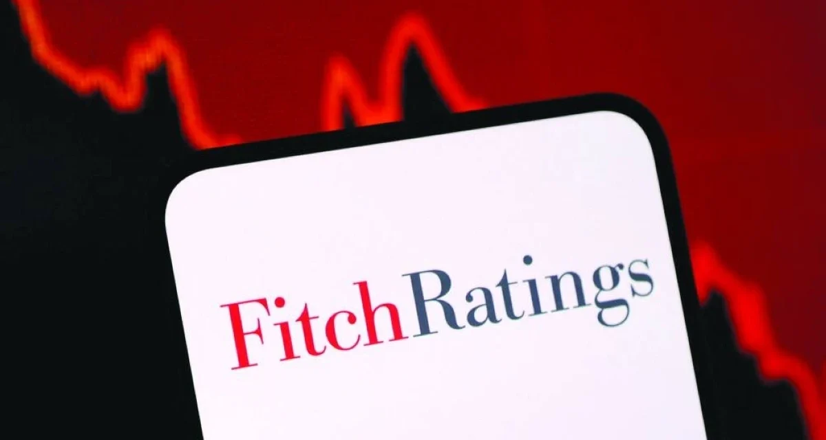 Fitch Ratings logo displayed on a smartphone with a falling market graph highlighting credit risk concerns.