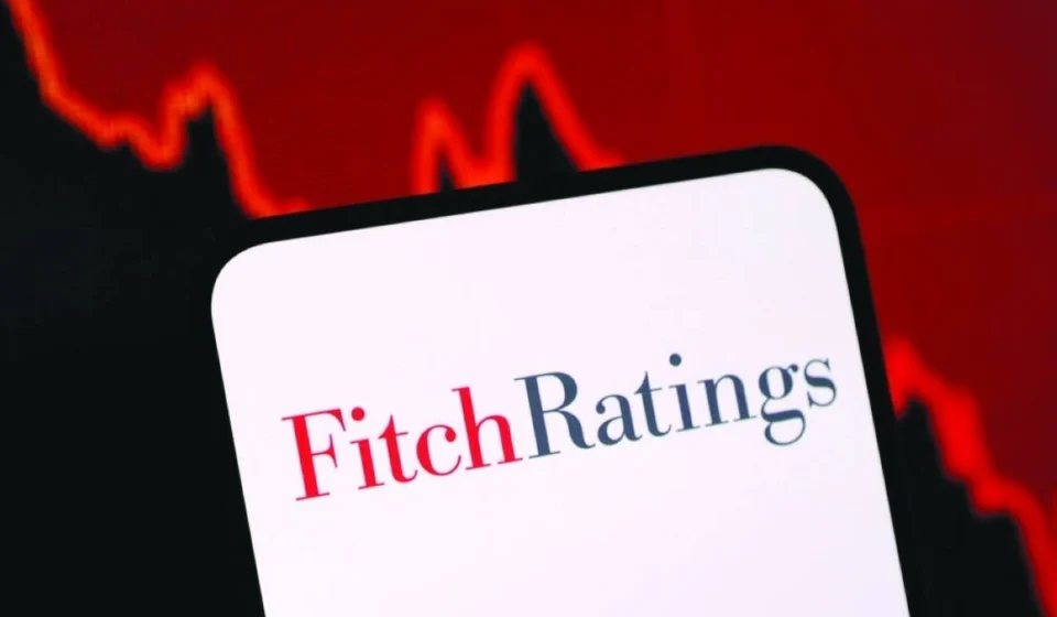 Fitch Ratings logo displayed on a smartphone with a falling market graph highlighting credit risk concerns.