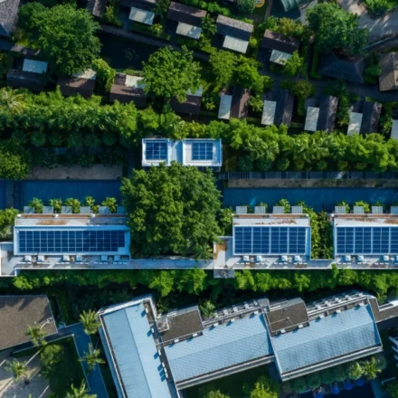 Aerial view of eco friendly residential buildings with rooftop solar panels surrounded by lush greenery.