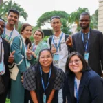 Youth delegates from diverse backgrounds gather outdoors during an international climate and sustainability event.