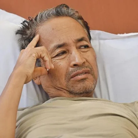 Man resting in a hospital bed during a hunger strike after police intervention over education protests.