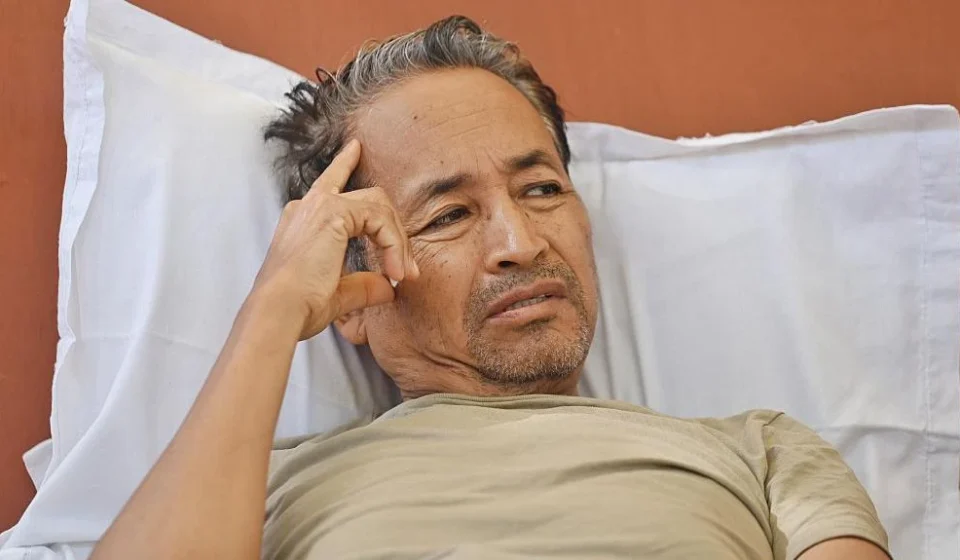 Man resting in a hospital bed during a hunger strike after police intervention over education protests.