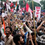Crowds of students wave flags and record a large protest rally demanding education reforms across India.