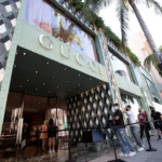 Gucci flagship store entrance with shoppers waiting outside, reflecting renewed luxury retail demand and growth.