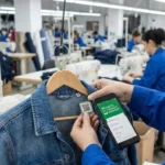 Garment worker scanning a QR code on a denim jacket for digital material traceability in a clothing factory.