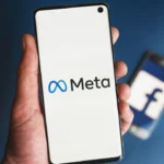 Meta logo displayed on a smartphone screen with a blurred Facebook logo in the background during lawsuit.