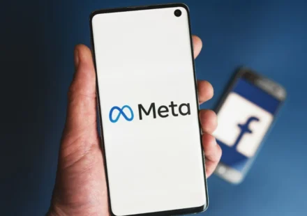 Meta logo displayed on a smartphone screen with a blurred Facebook logo in the background during lawsuit.