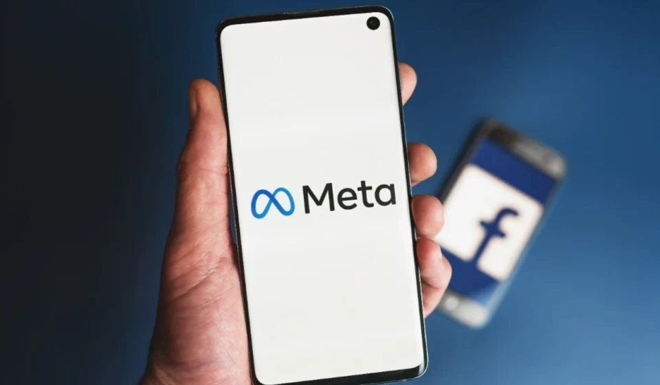 Meta logo displayed on a smartphone screen with a blurred Facebook logo in the background during lawsuit.