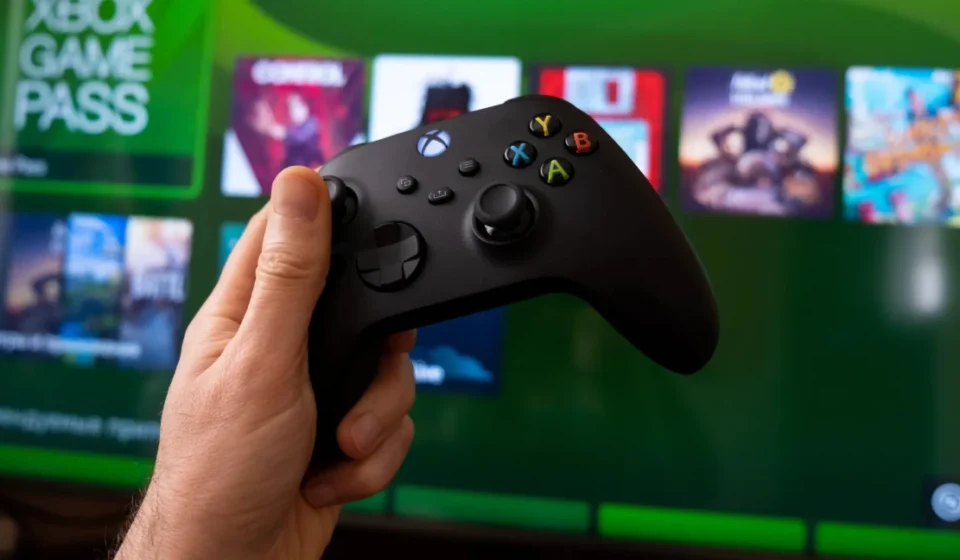 Black gaming controller held before a cloud gaming interface on a screen showing next generation console services.