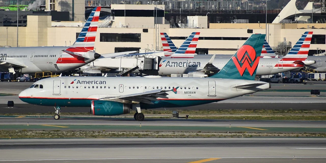 American Airlines and another commercial jet taxi on an airport runway amid busy terminal operations and traffic.