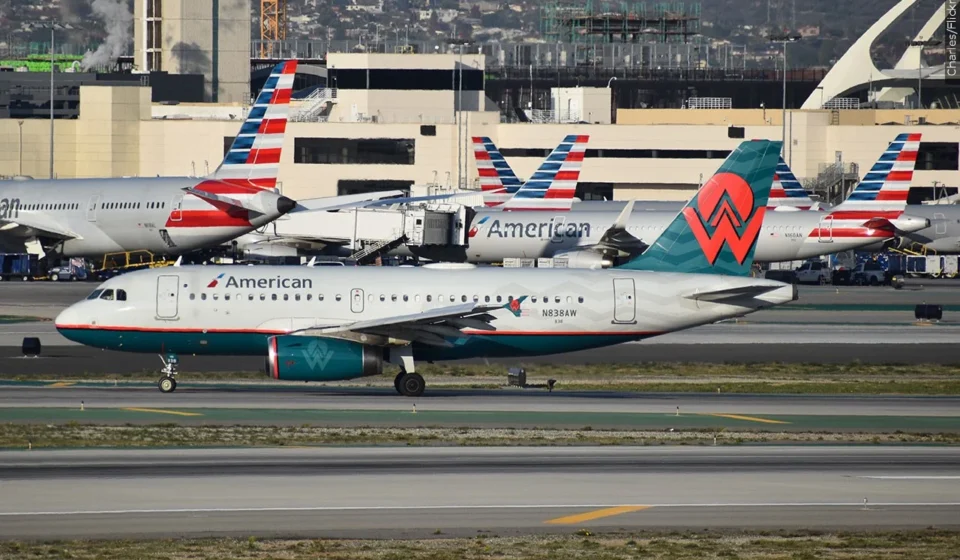 American Airlines and another commercial jet taxi on an airport runway amid busy terminal operations and traffic.
