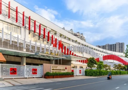 Canadian International School campus building in Vietnam with modern architecture and flags lining entrance road.