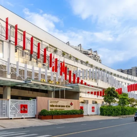 Canadian International School campus building in Vietnam with modern architecture and flags lining entrance road.