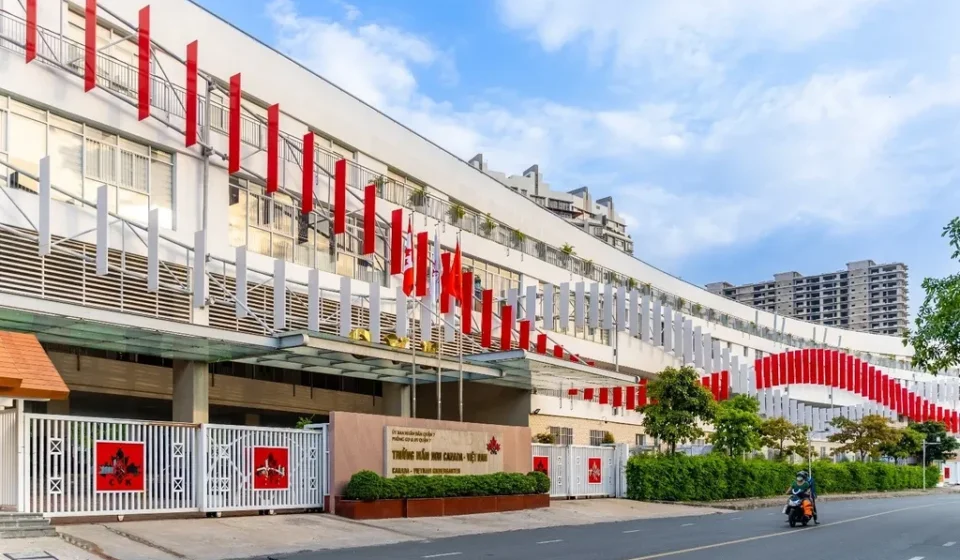 Canadian International School campus building in Vietnam with modern architecture and flags lining entrance road.