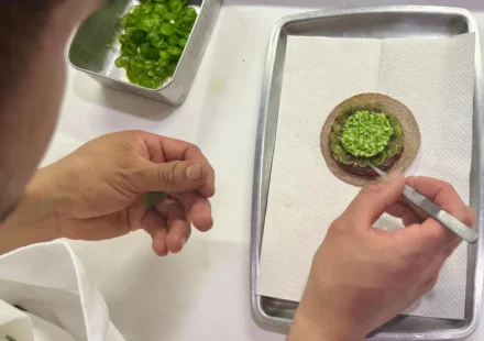 Chef carefully plating an elegant Mexican fine dining dish before service at a Michelin star restaurant.