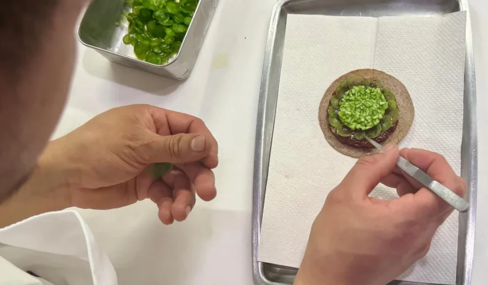 Chef carefully plating an elegant Mexican fine dining dish before service at a Michelin star restaurant.