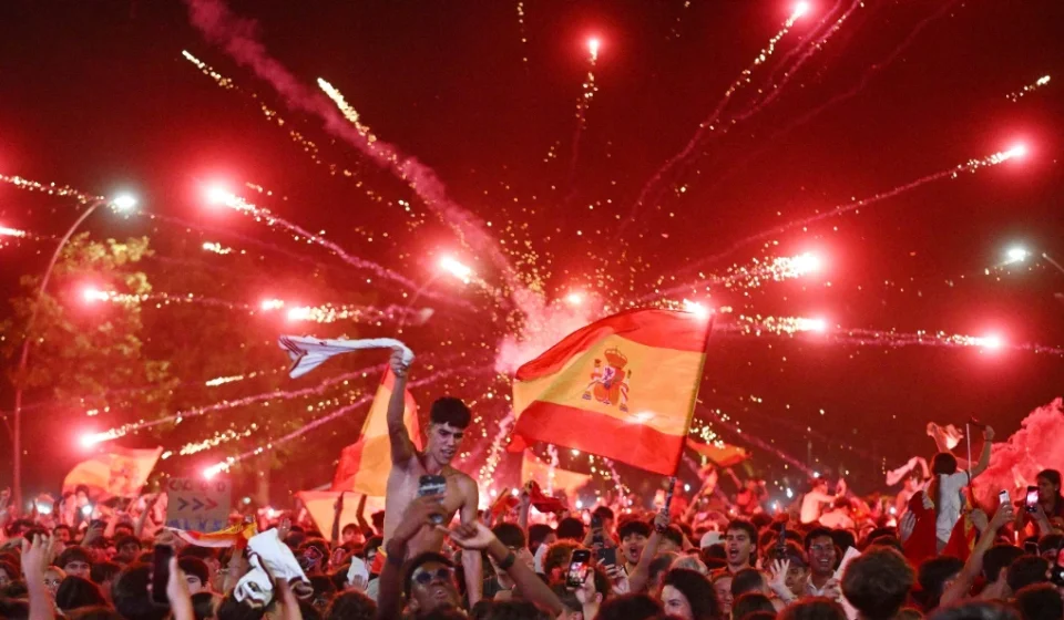 Crowds wave Spanish flags beneath fireworks as Madrid celebrates world title victory together. joy!!