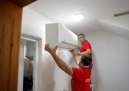 Technicians install a wall mounted smart air conditioner in a home to improve energy efficient cooling during heatwaves.