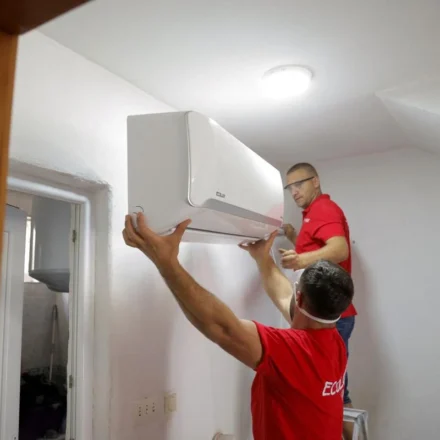Technicians install a wall mounted smart air conditioner in a home to improve energy efficient cooling during heatwaves.
