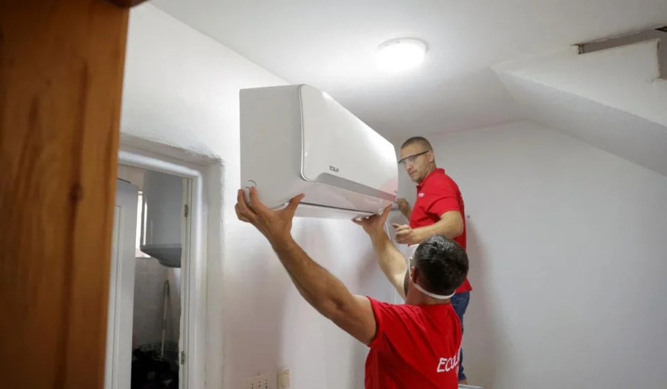 Technicians install a wall mounted smart air conditioner in a home to improve energy efficient cooling during heatwaves.
