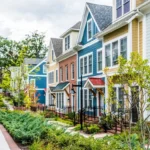 Modern colorful townhouses with landscaped walkway showcasing sustainable residential neighborhood design.