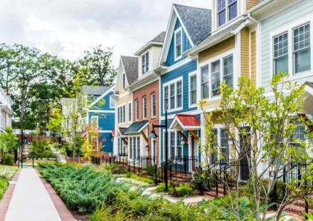 Modern colorful townhouses with landscaped walkway showcasing sustainable residential neighborhood design.