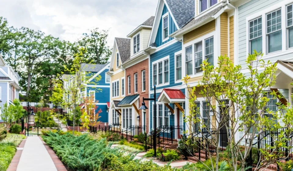 Modern colorful townhouses with landscaped walkway showcasing sustainable residential neighborhood design.