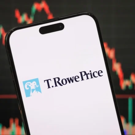 Smartphone displaying T. Rowe Price logo with cryptocurrency market chart blurred behind on screen.