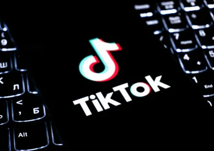 TikTok logo displayed on a smartphone over a keyboard, illustrating updated live shopping policies.!
