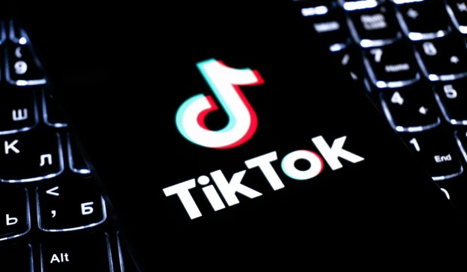 TikTok logo displayed on a smartphone over a keyboard, illustrating updated live shopping policies.!