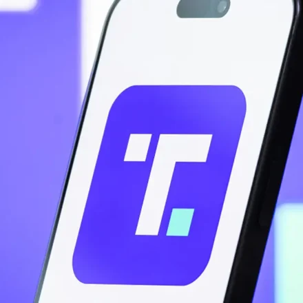 Smartphone displaying Trump Media app logo on purple background illustrating premium social platform