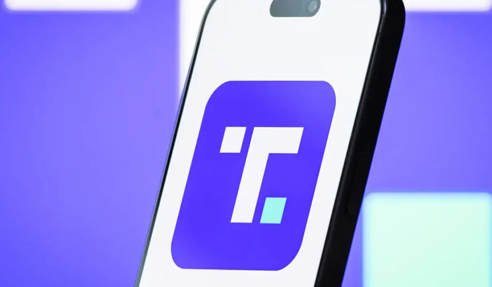 Smartphone displaying Trump Media app logo on purple background illustrating premium social platform