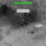 Thermal aerial view shows explosion near a military target during nighttime strike in Middle East.
