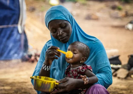 Mother feeding child with nutritional meal highlights hunger relief efforts amid global food crisis.