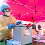 Healthcare worker handles medical supplies at an Ebola response site as Uganda officially ends outbreak control.